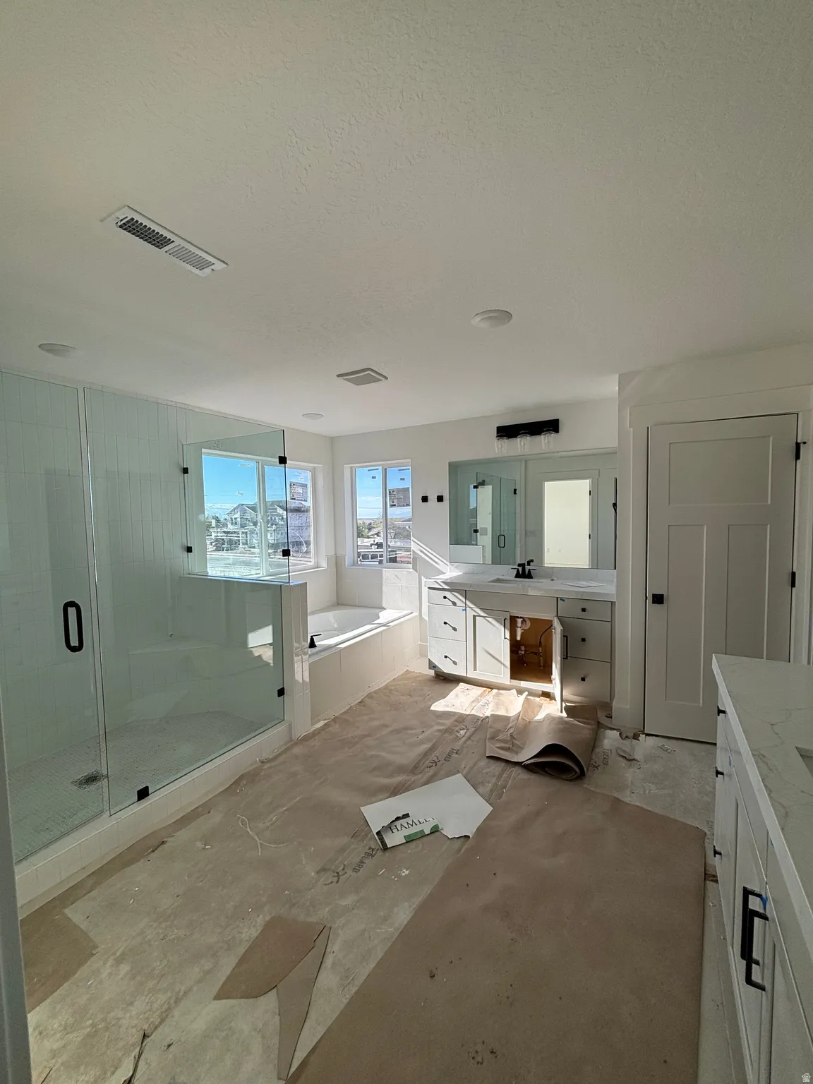 Full bath featuring vanity, a shower stall, a garden tub, and a textured ceiling