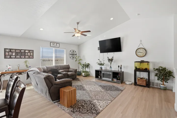 Living area with a ceiling fan, light wood-style floors, lofted ceiling, and recessed lighting