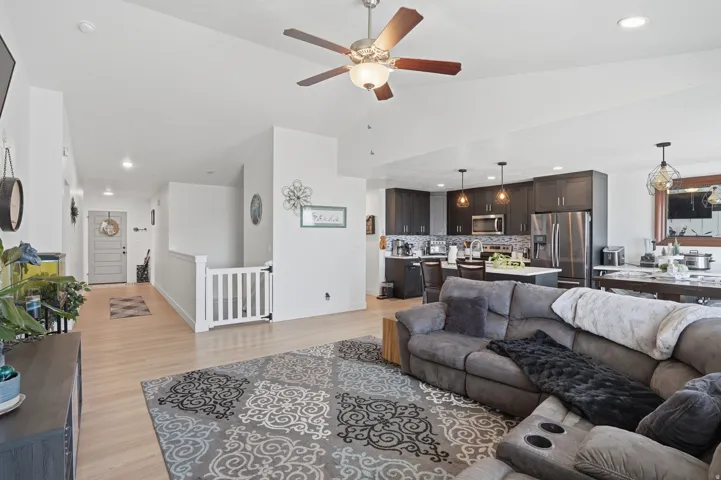 Living room featuring light wood-style flooring, recessed lighting, a ceiling fan, and vaulted ceiling