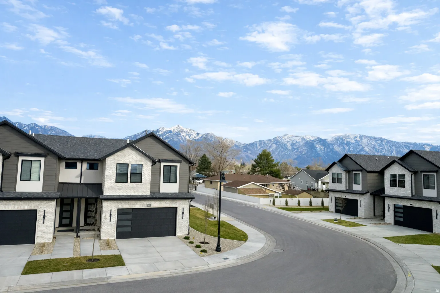 View of asphalt road featuring a residential view, sidewalks, curbs, and a mountain view