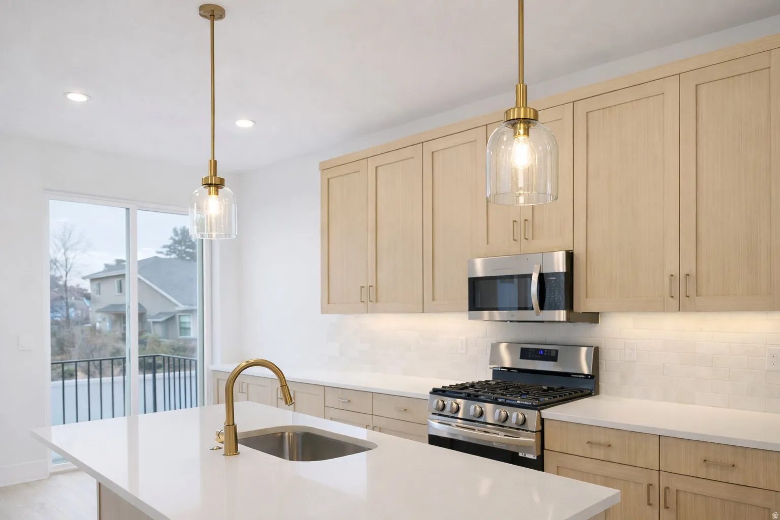 Kitchen featuring light wood finish cabinetry, stainless steel appliances, and pendant lighting
