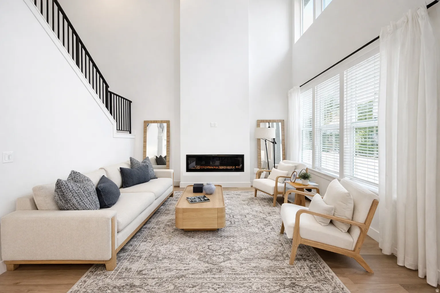 Living area featuring a high ceiling, a glass covered fireplace, and wood finished floors