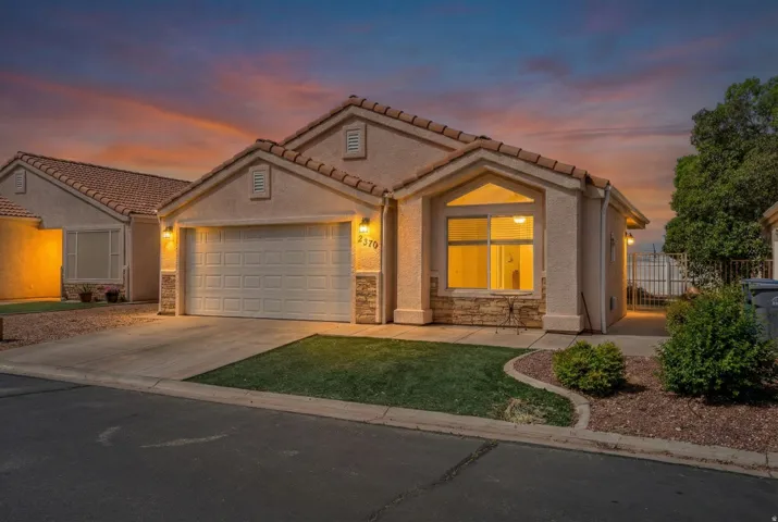 Mediterranean / spanish house with driveway, an attached garage, stone siding, stucco siding, and a tiled roof