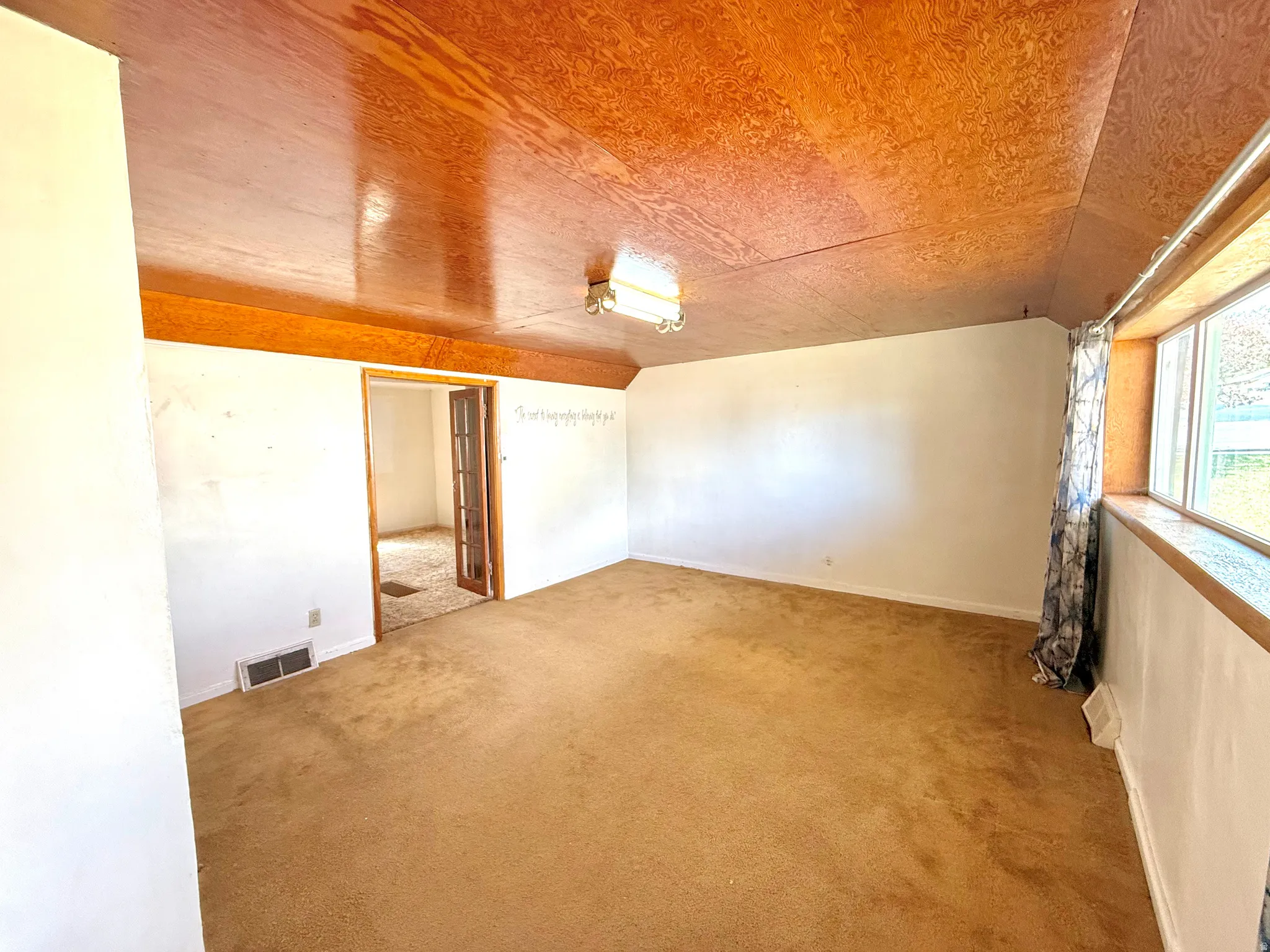 Empty room featuring lofted ceiling and light colored carpet