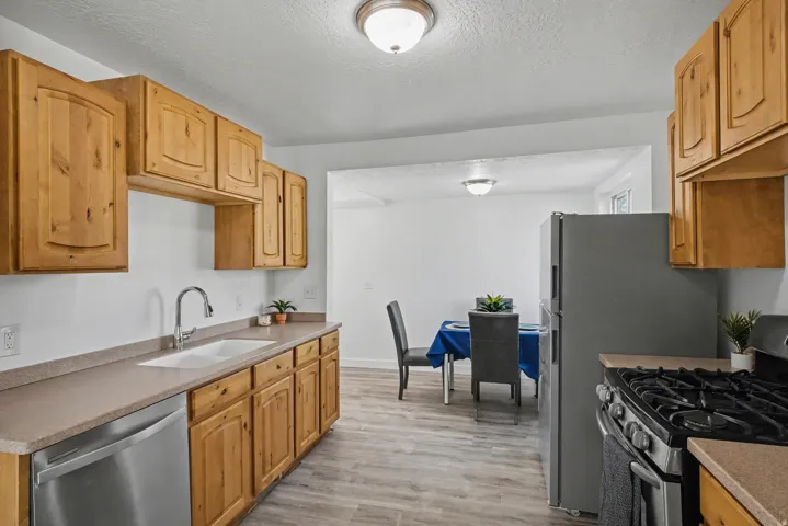 Kitchen featuring stainless steel appliances, light wood-style flooring, a textured ceiling, and wood finish cabinets
