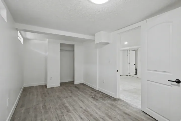 Unfurnished bedroom featuring a textured ceiling, light wood-style flooring, and a closet