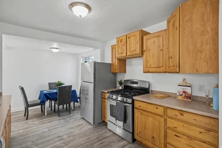 Kitchen featuring gas range, light wood finished floors, a textured ceiling, and light countertops