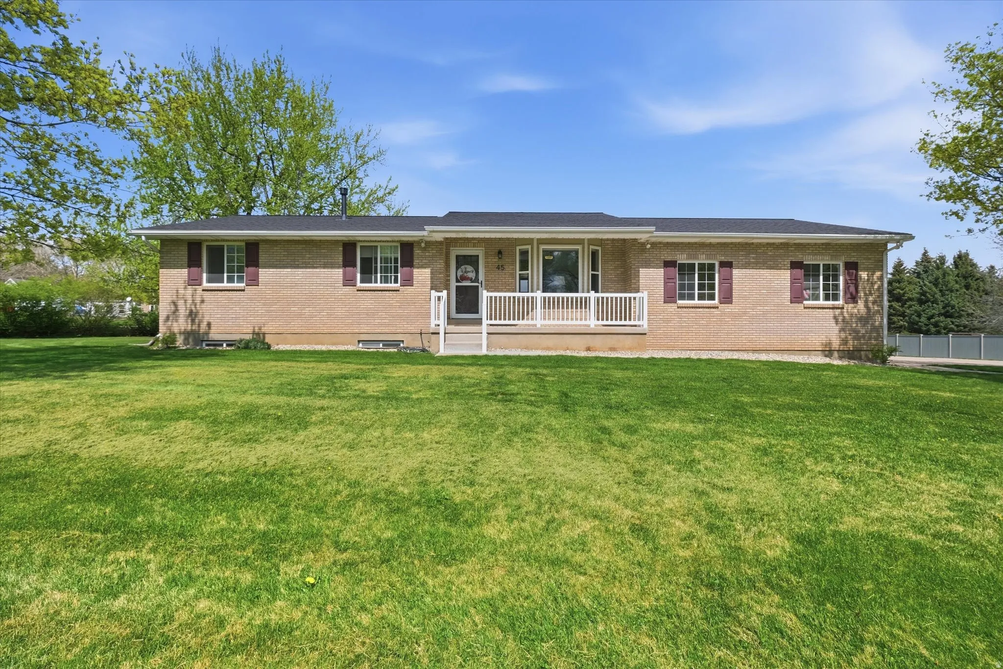 Ranch-style house featuring a porch, brick siding, and a front lawn