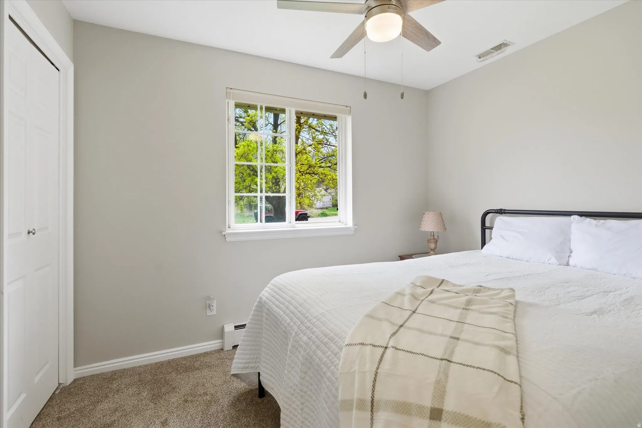 Bedroom featuring carpet, a ceiling fan, a closet, and a baseboard radiator