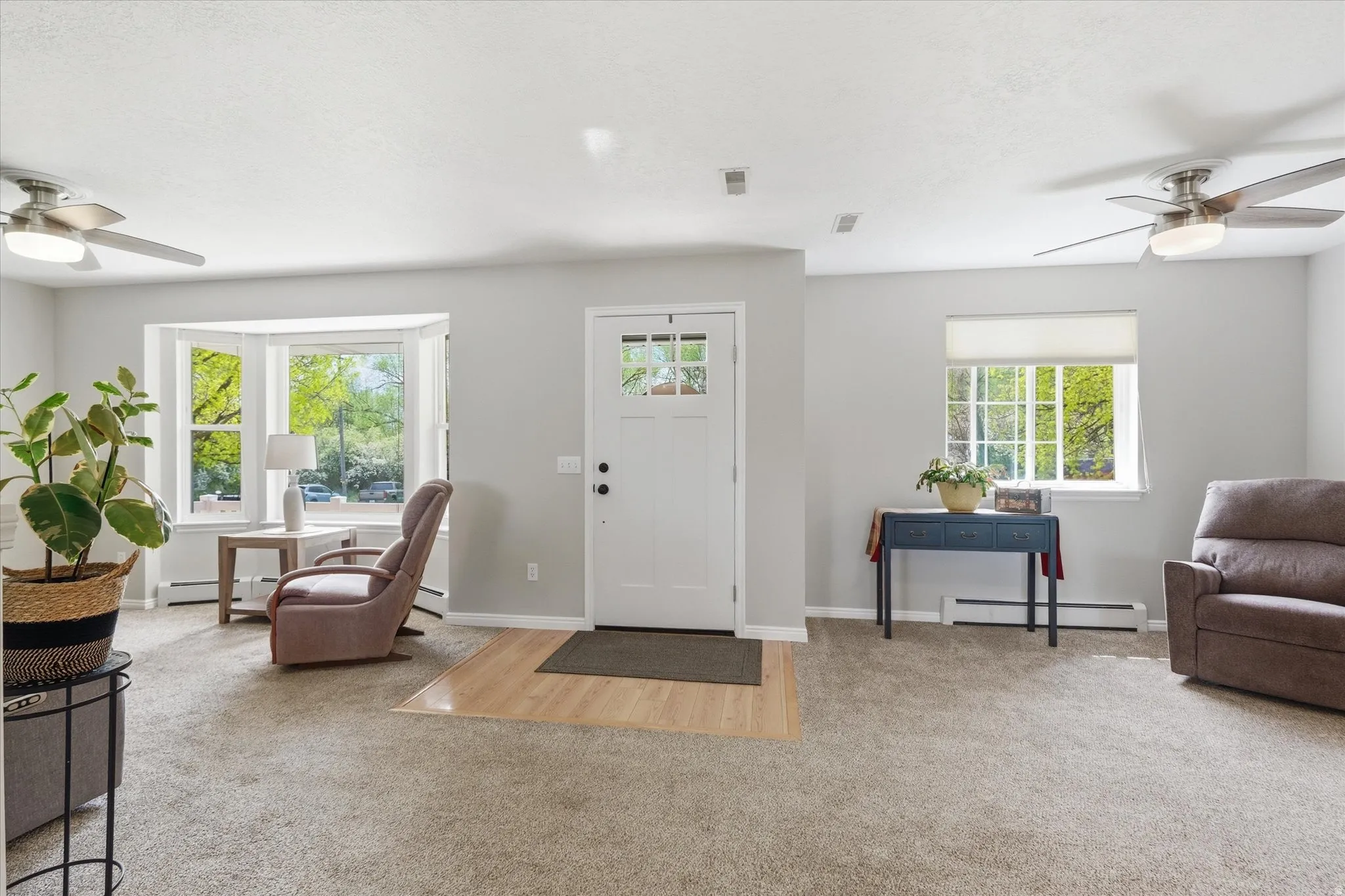 Foyer entrance with ceiling fan, light colored carpet, and a baseboard radiator