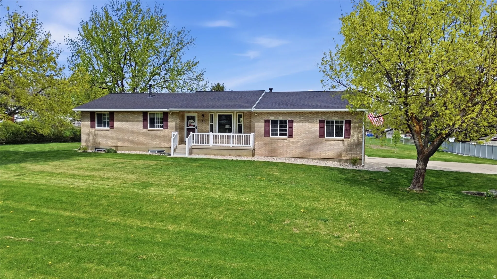 Ranch-style home with a front lawn, brick siding, and covered porch