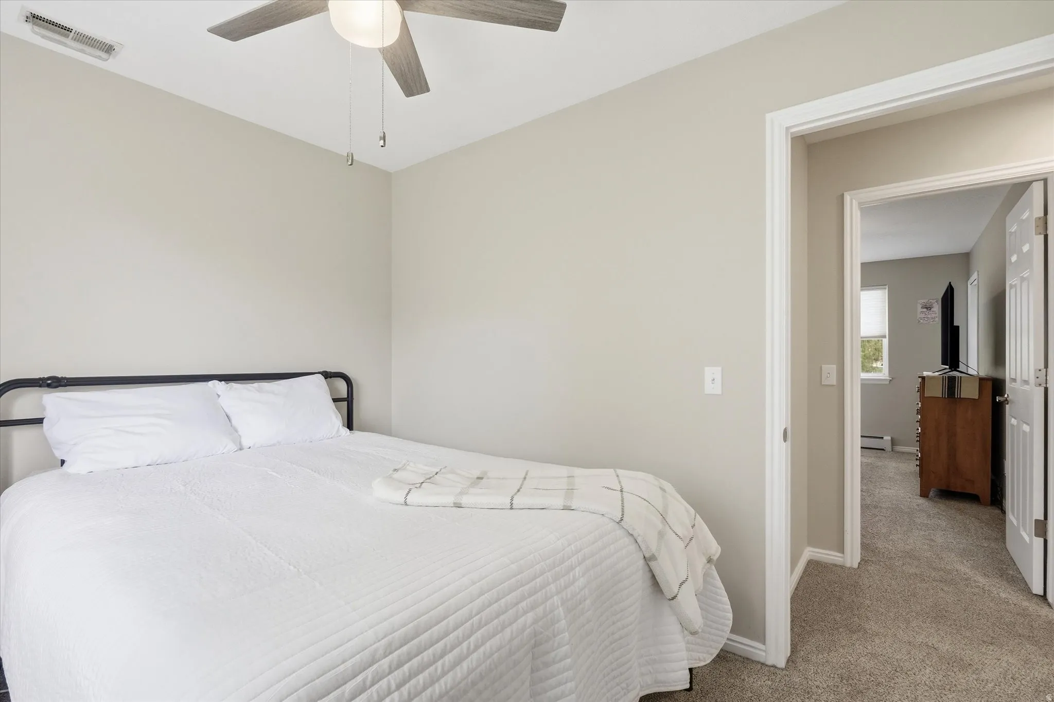 Bedroom featuring carpet flooring, a ceiling fan, and a baseboard radiator