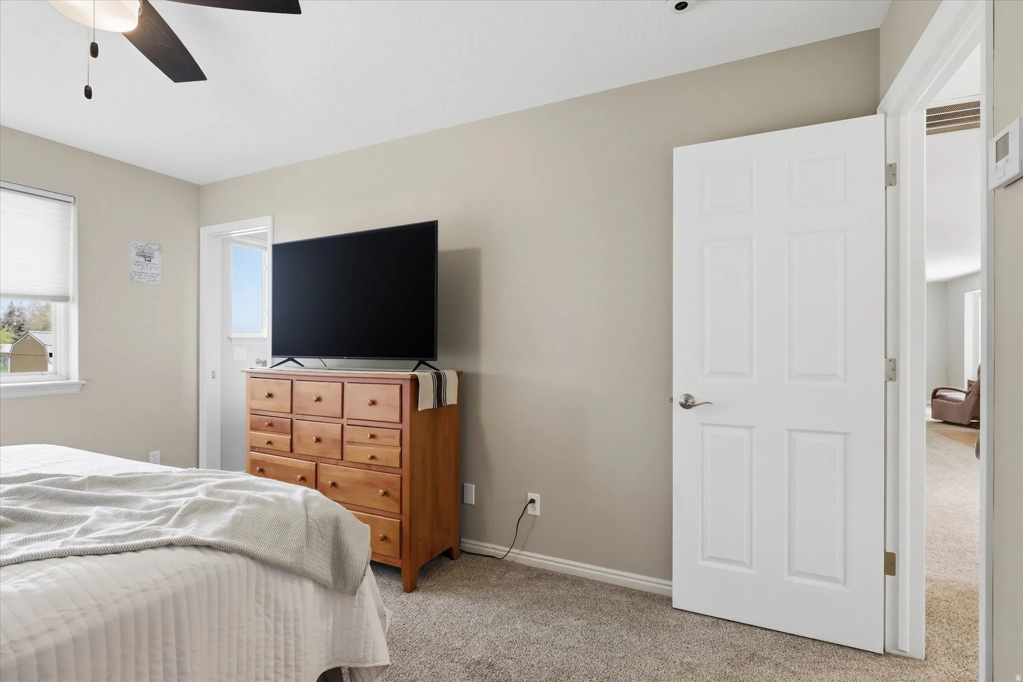Bedroom with light colored carpet and a ceiling fan