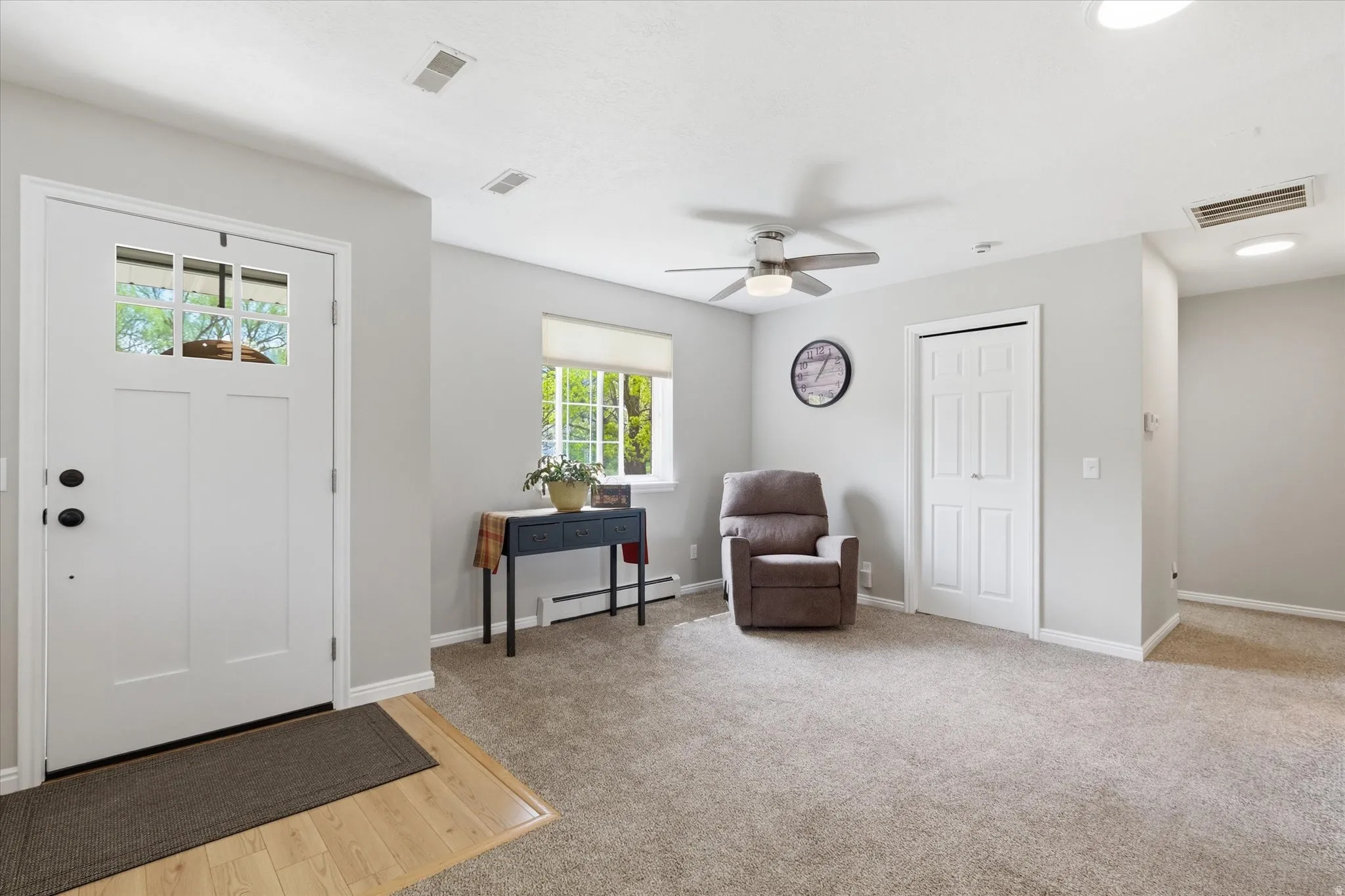 Entrance foyer featuring ceiling fan, baseboard heating, light carpet, and light wood-style flooring