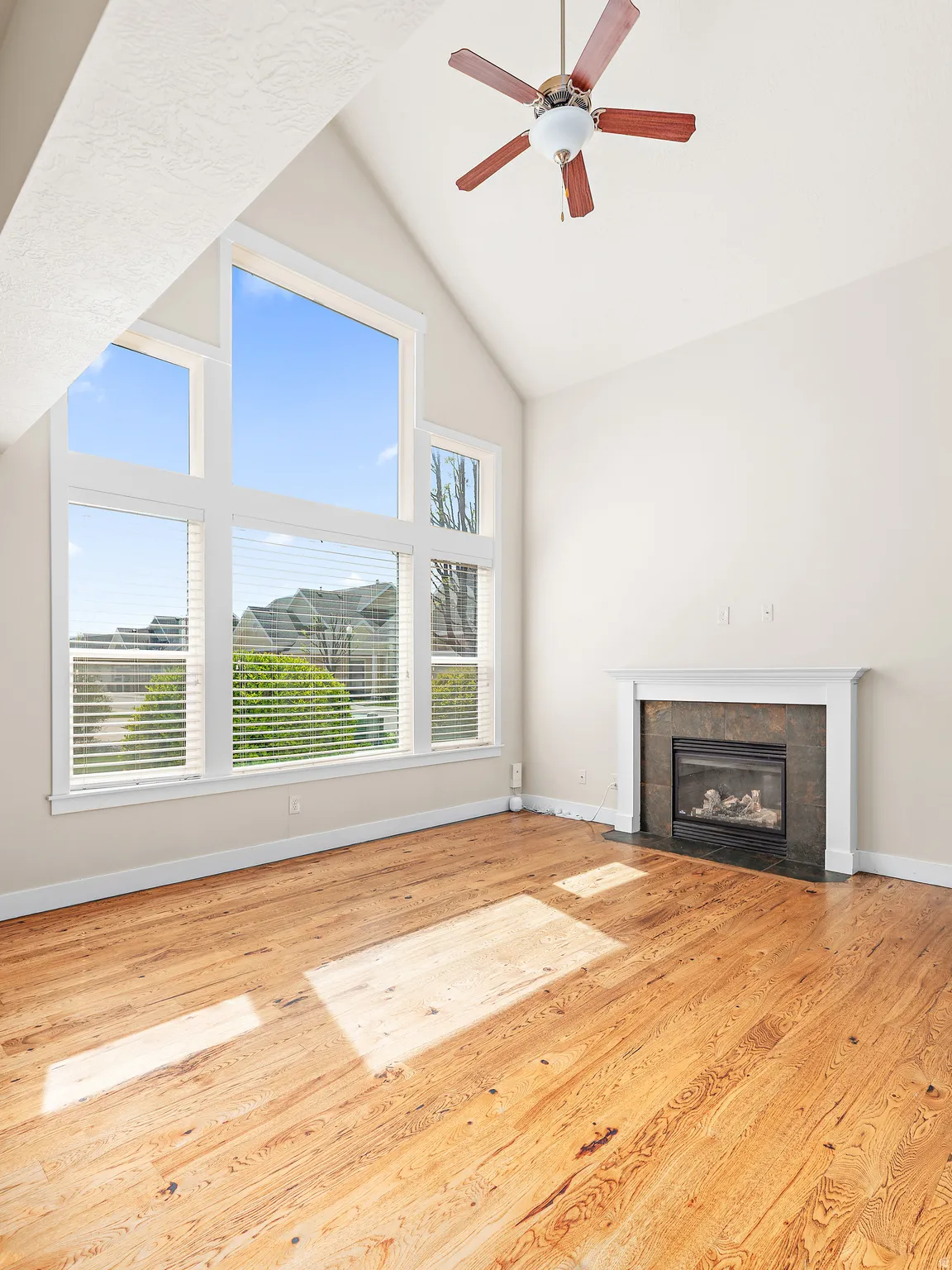 Unfurnished living room featuring a fireplace, ceiling fan, light wood-style floors, and vaulted ceiling