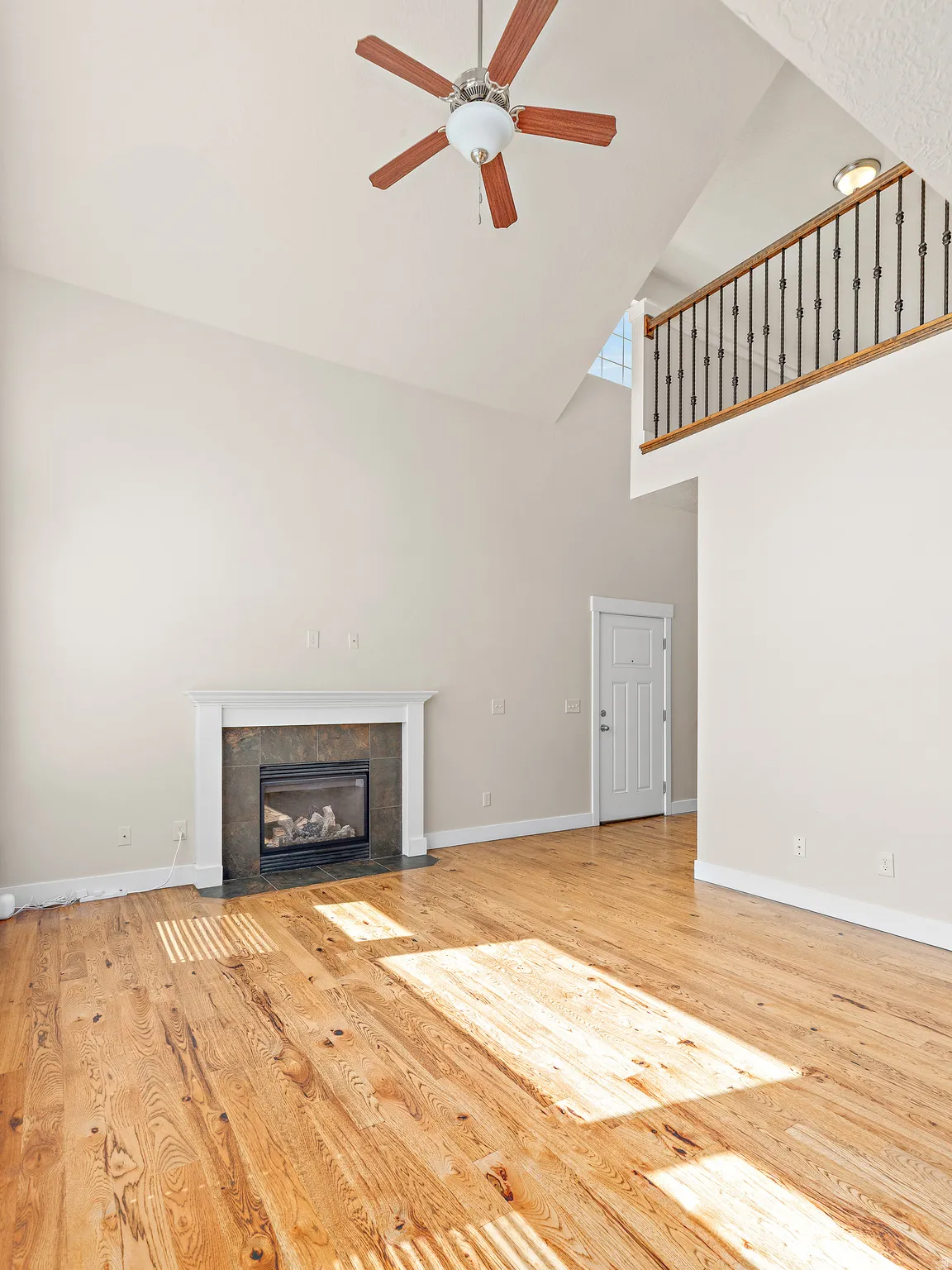 Unfurnished living room featuring a ceiling fan, light wood-type flooring, a fireplace, and vaulted ceiling