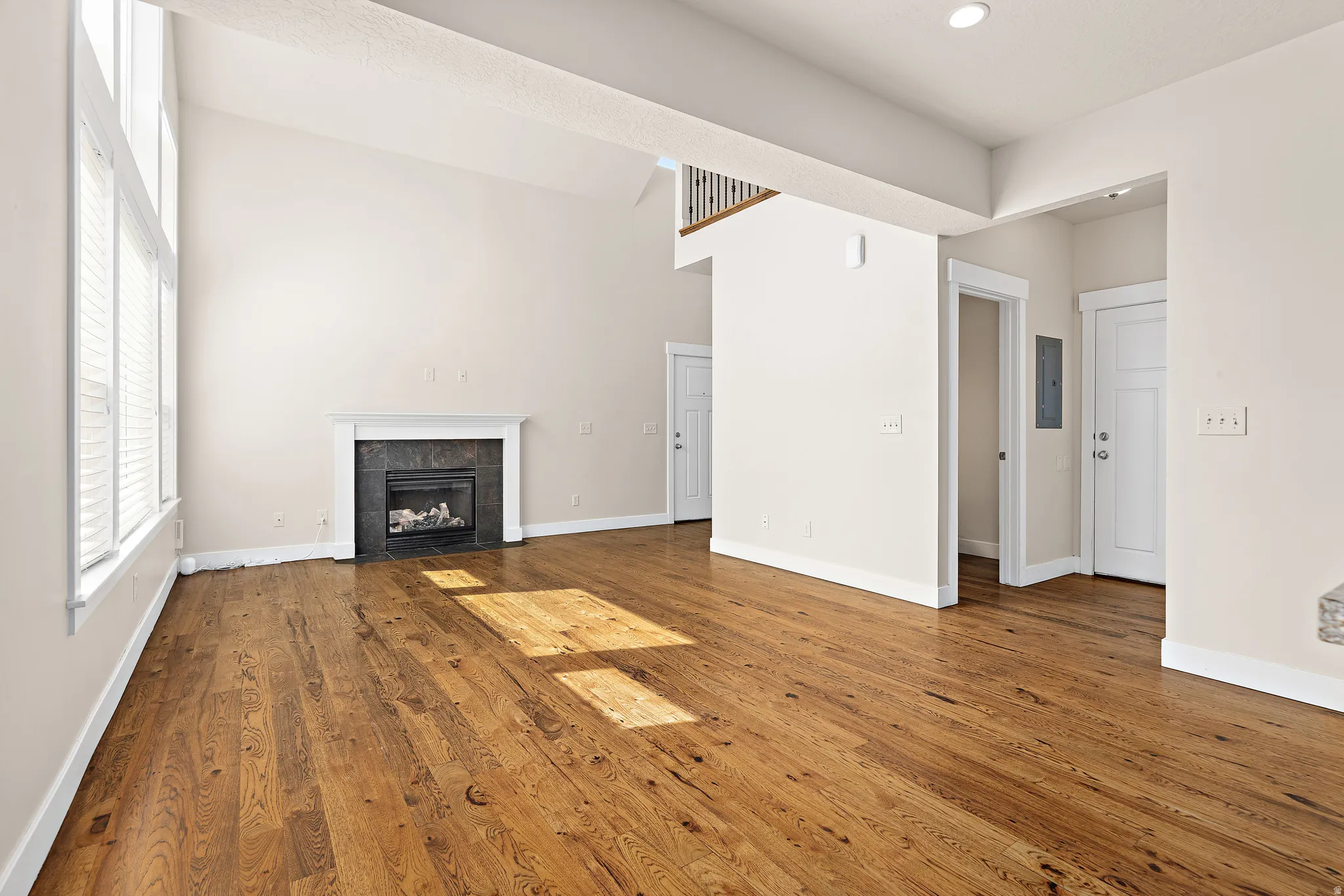 Unfurnished living room with hardwood / wood-style flooring, a tile fireplace, and electric panel