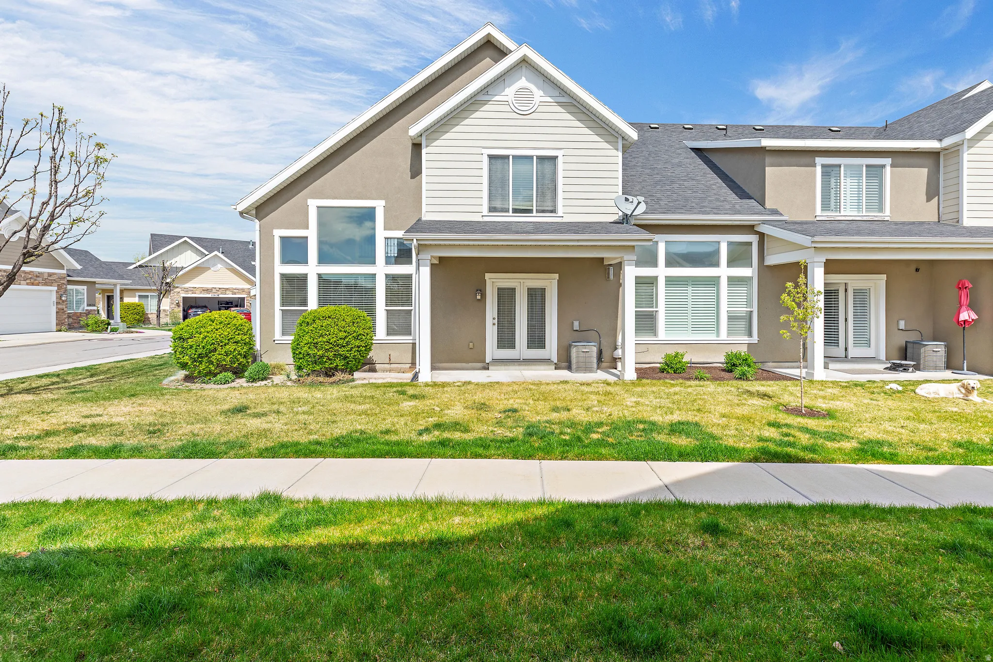 Traditional home with french doors, a patio, stucco siding, and a front lawn