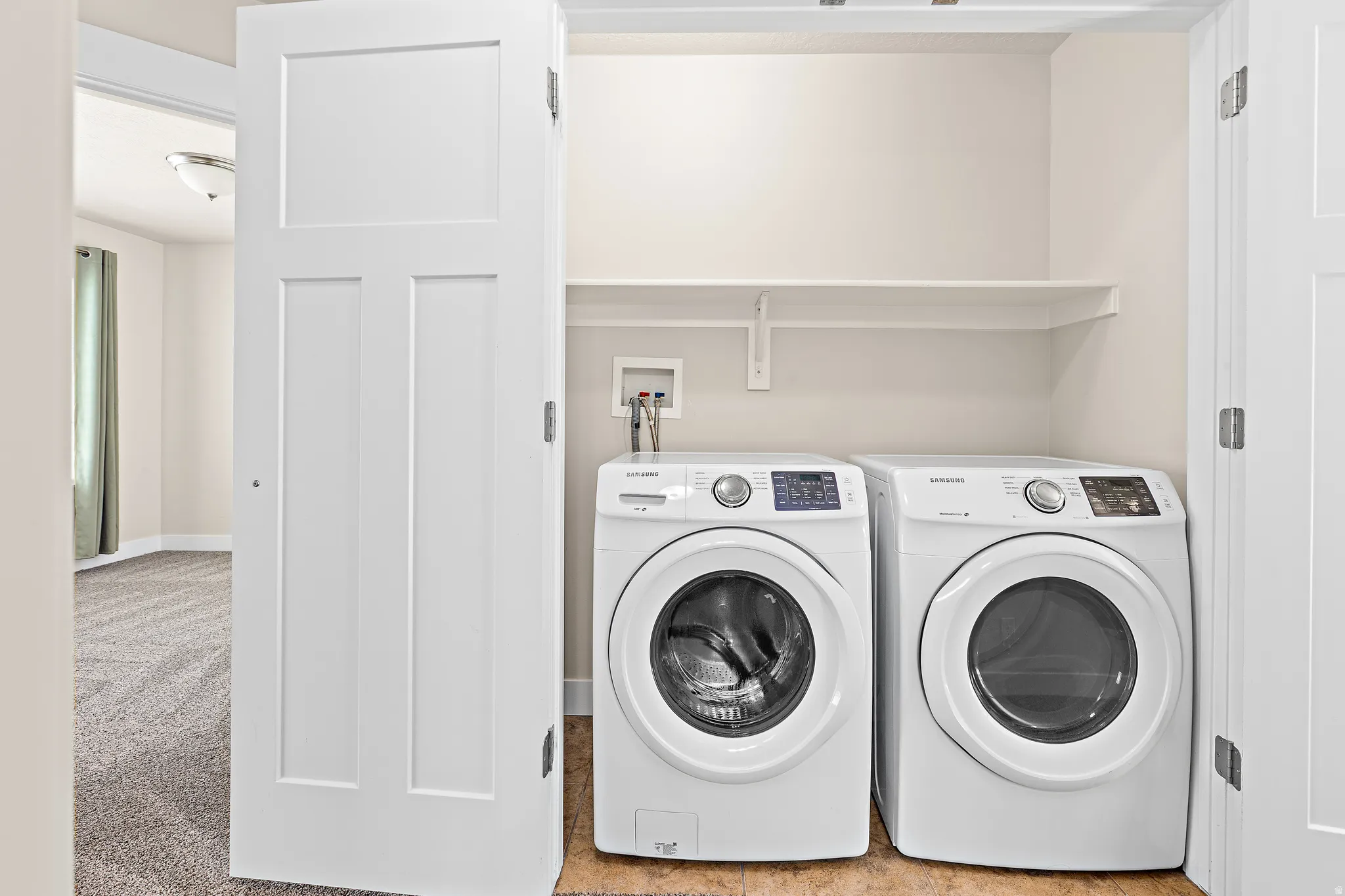 Laundry area featuring light carpet and washer and dryer