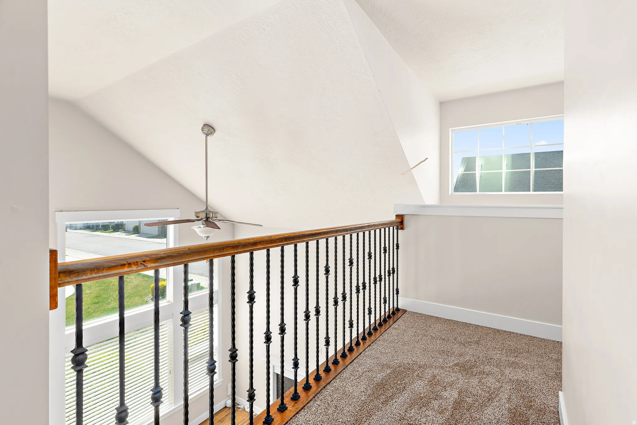 Hallway with carpet flooring and lofted ceiling