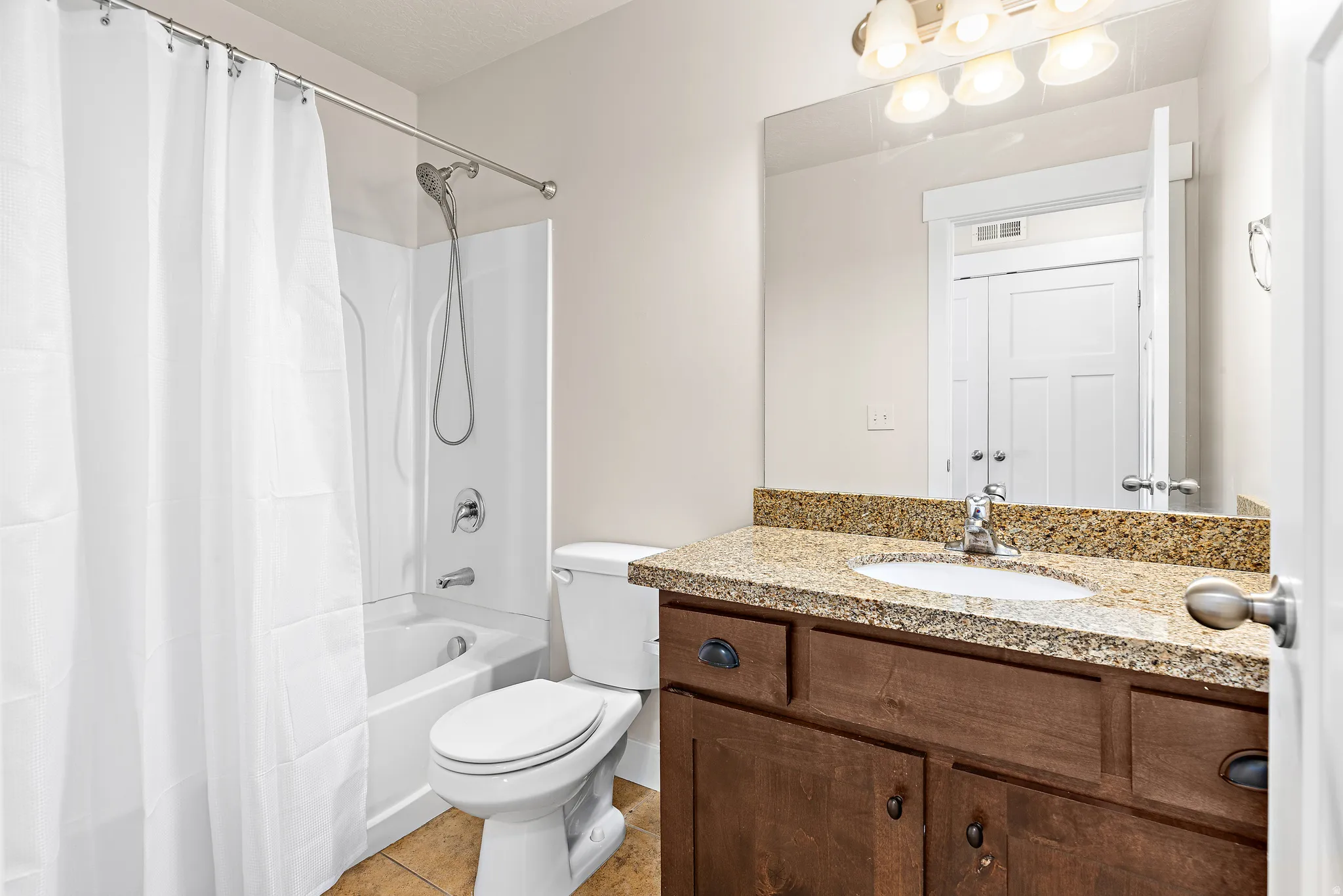 Full bathroom featuring vanity, shower / tub combo, and light tile patterned floors