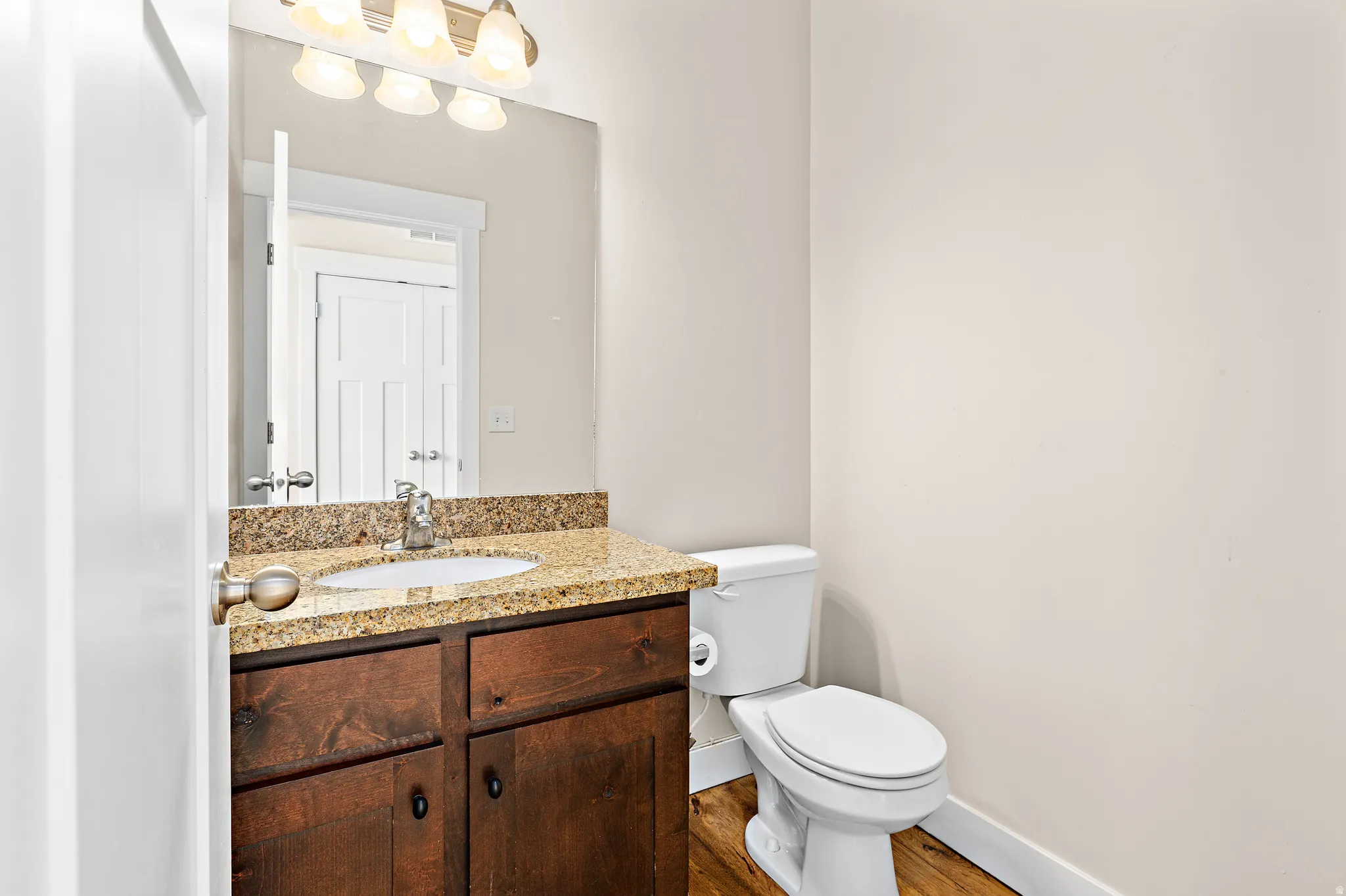 Half bathroom with vanity and dark wood-type flooring