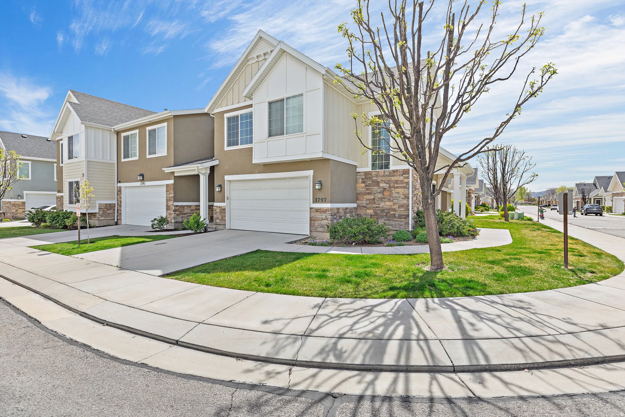 Craftsman inspired home with a residential view, an attached garage, board and batten siding, driveway, and stone siding