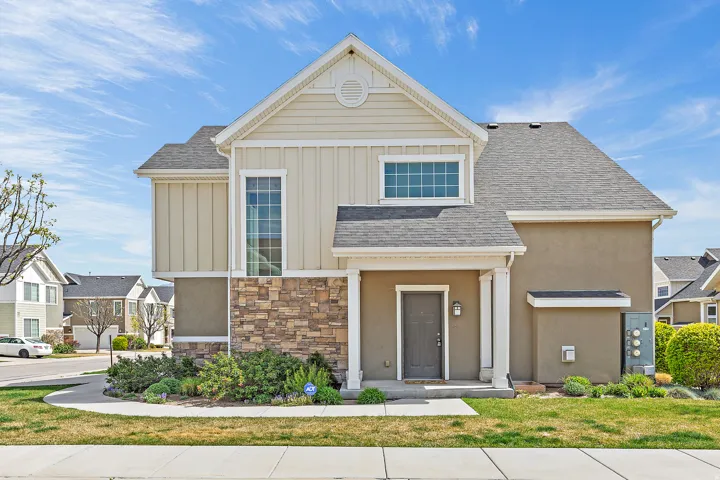 View of front of house featuring board and batten siding, roof with shingles, stone siding, a front lawn, and a residential view