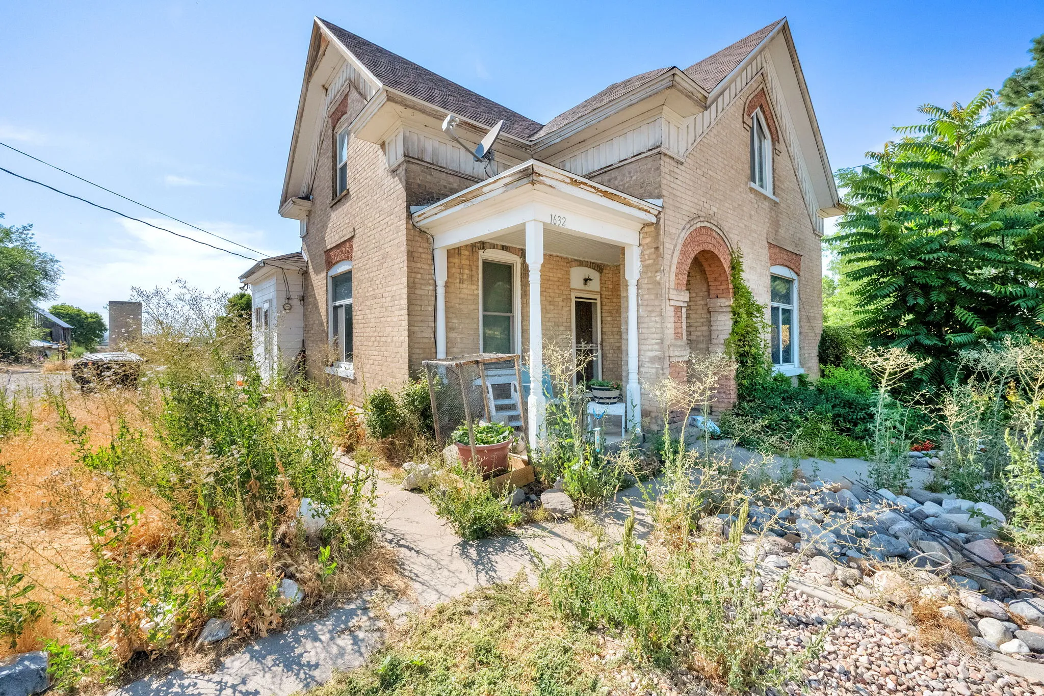 View of front facade with brick siding, a porch, and roof with shingles