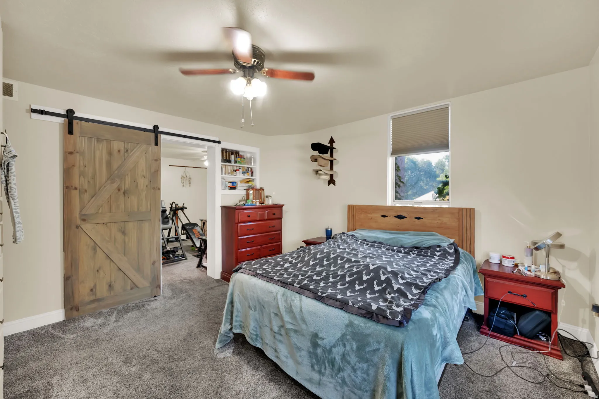Bedroom featuring carpet floors, a barn door, and ceiling fan