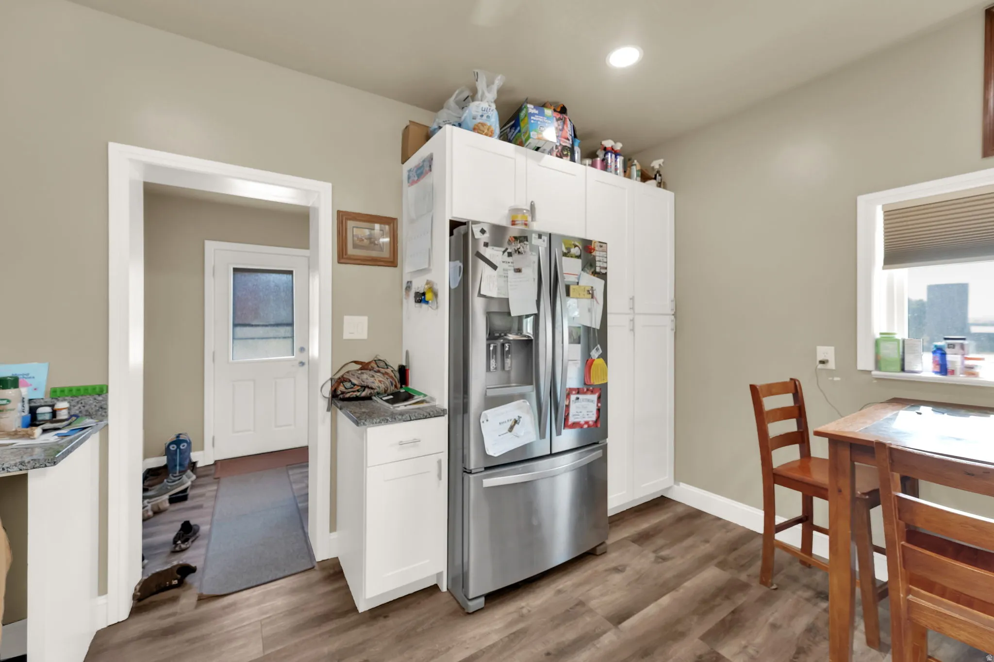 Kitchen with stainless steel fridge, white cabinetry, dark wood finished floors, and dark stone countertops