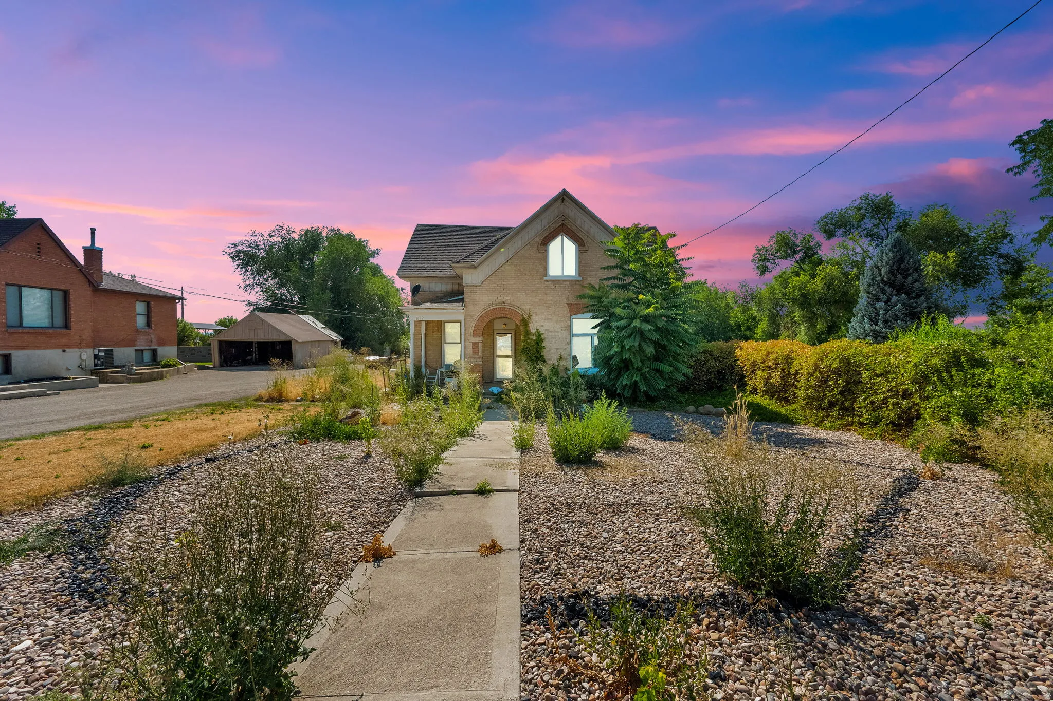 View of front of home featuring brick siding and an outbuilding