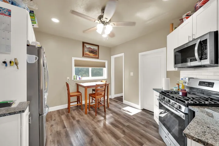 Kitchen with stainless steel appliances, white cabinetry, dark stone counters, dark wood finished floors, and recessed lighting