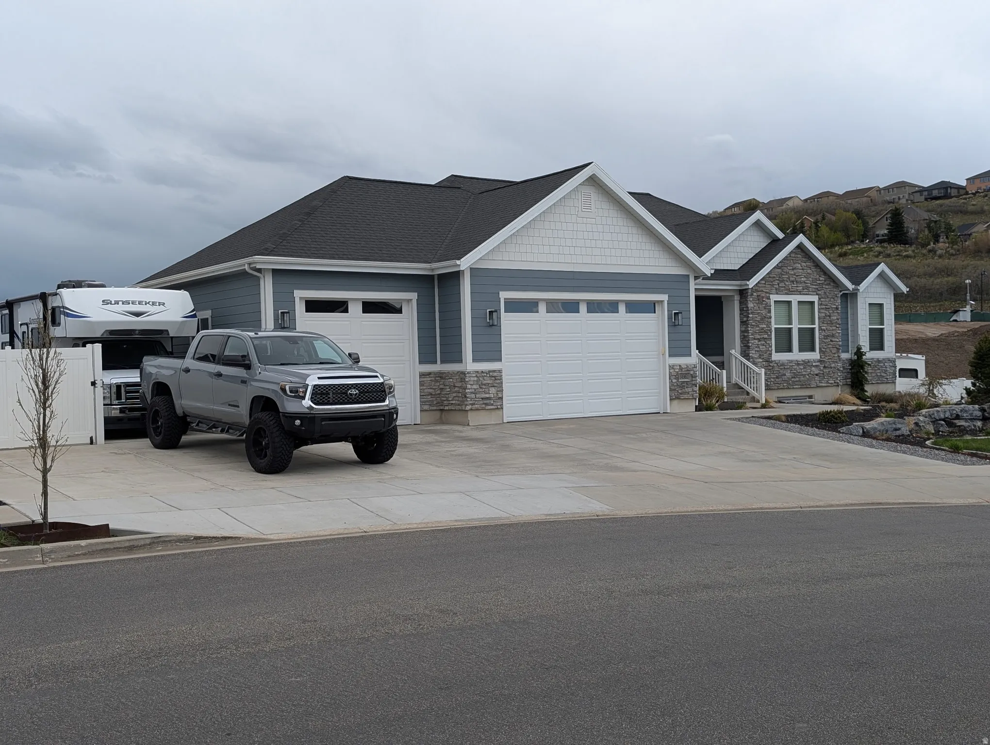 Craftsman house with a garage, stone siding, and concrete driveway