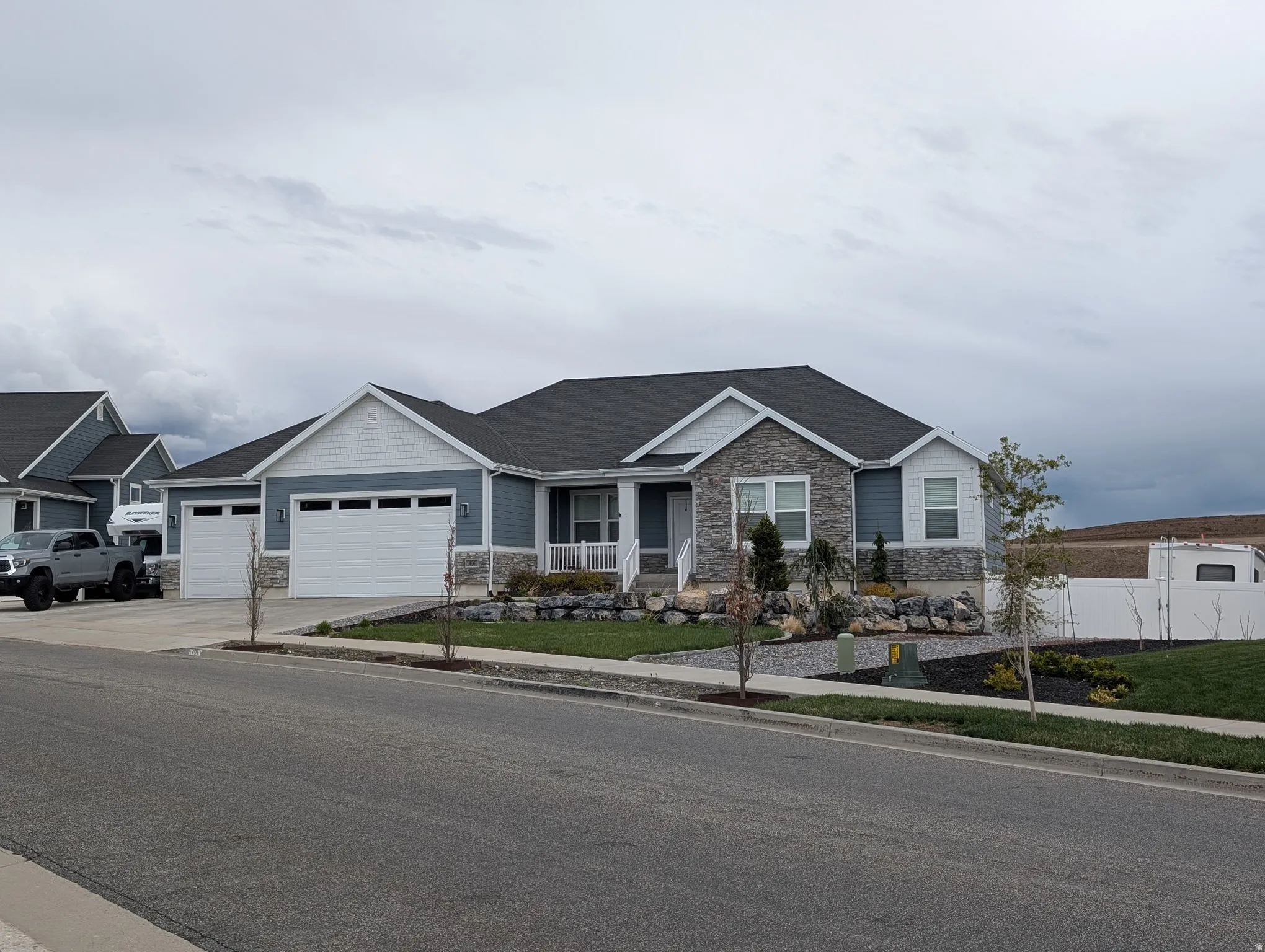View of front facade featuring stone siding, covered porch, an attached garage, concrete driveway, and a shingled roof