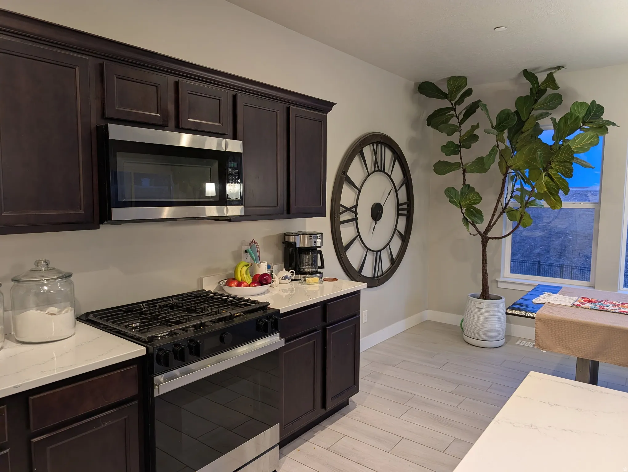 Kitchen featuring stainless steel appliances, dark wood finish cabinets, light stone countertops, and wood finish floors