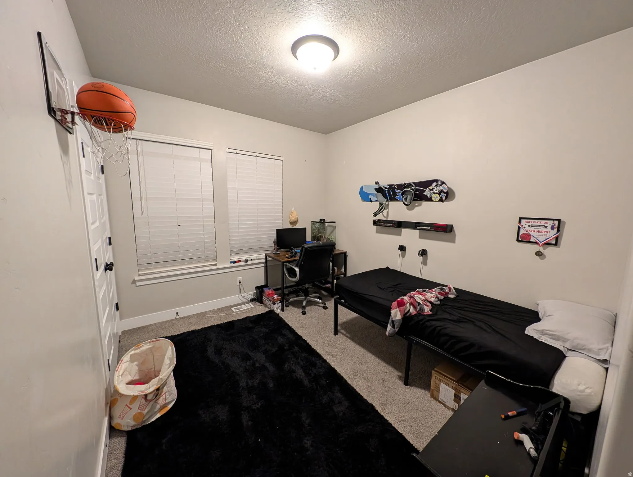 Carpeted bedroom with a textured ceiling and a desk