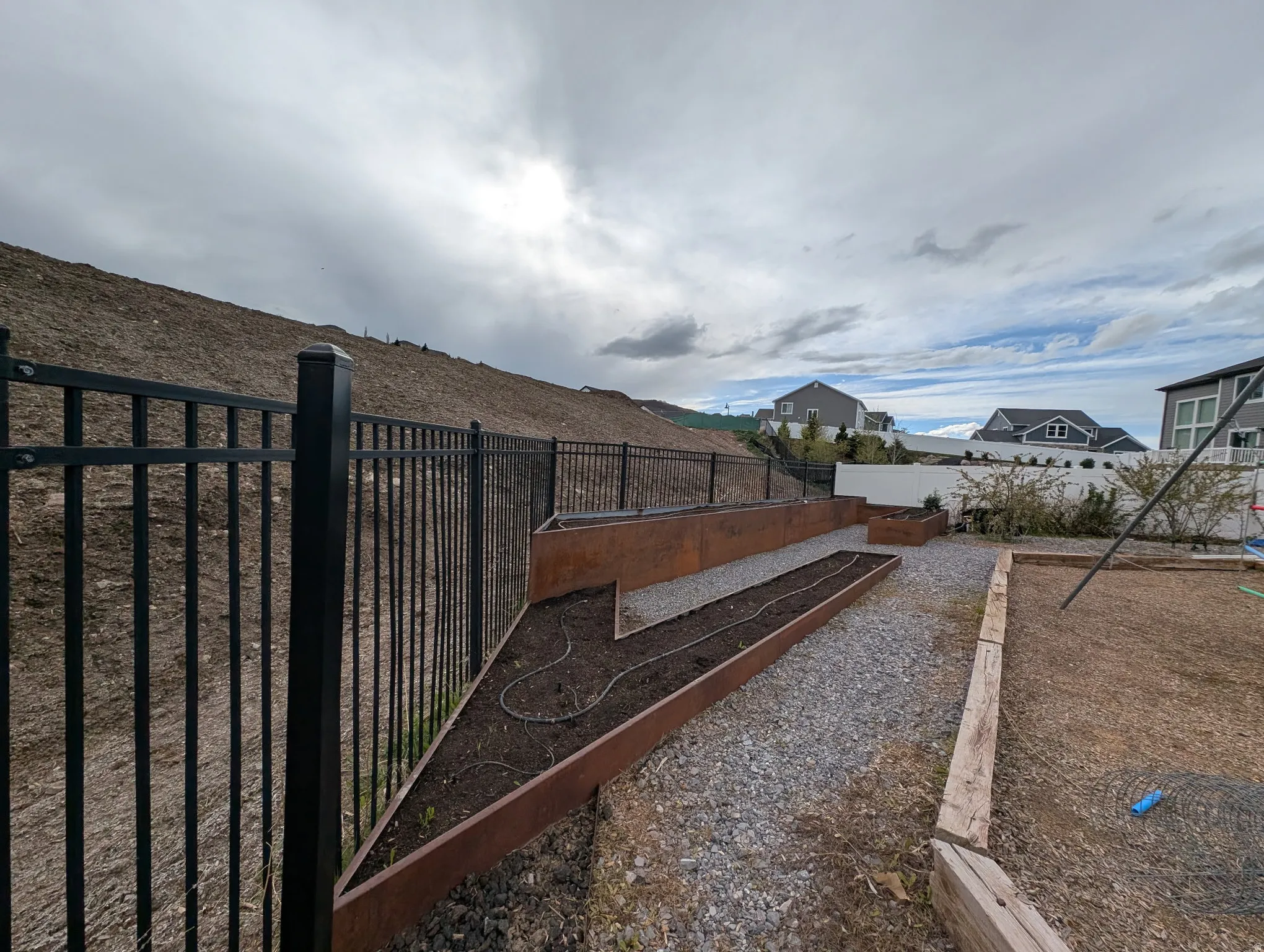 Fenced backyard featuring a vegetable garden and a residential view