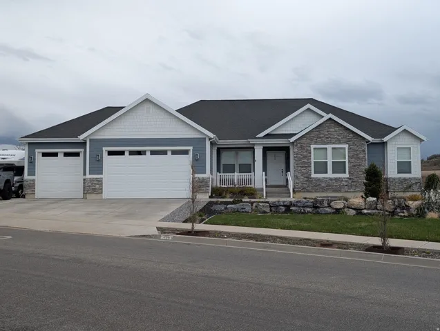 Craftsman house with stone siding, a garage, driveway, and a porch