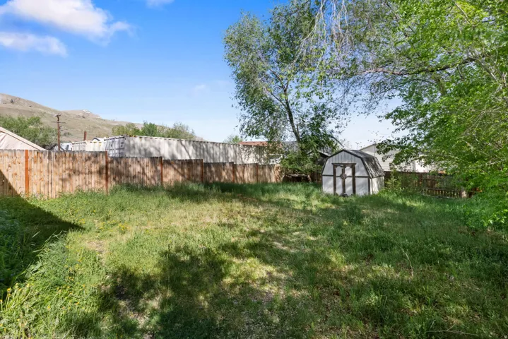 Fenced backyard featuring a storage unit