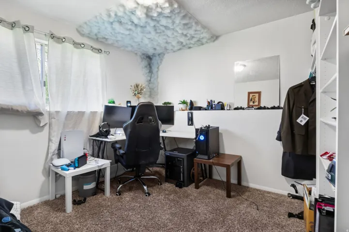 Carpeted home office featuring baseboards and a textured ceiling