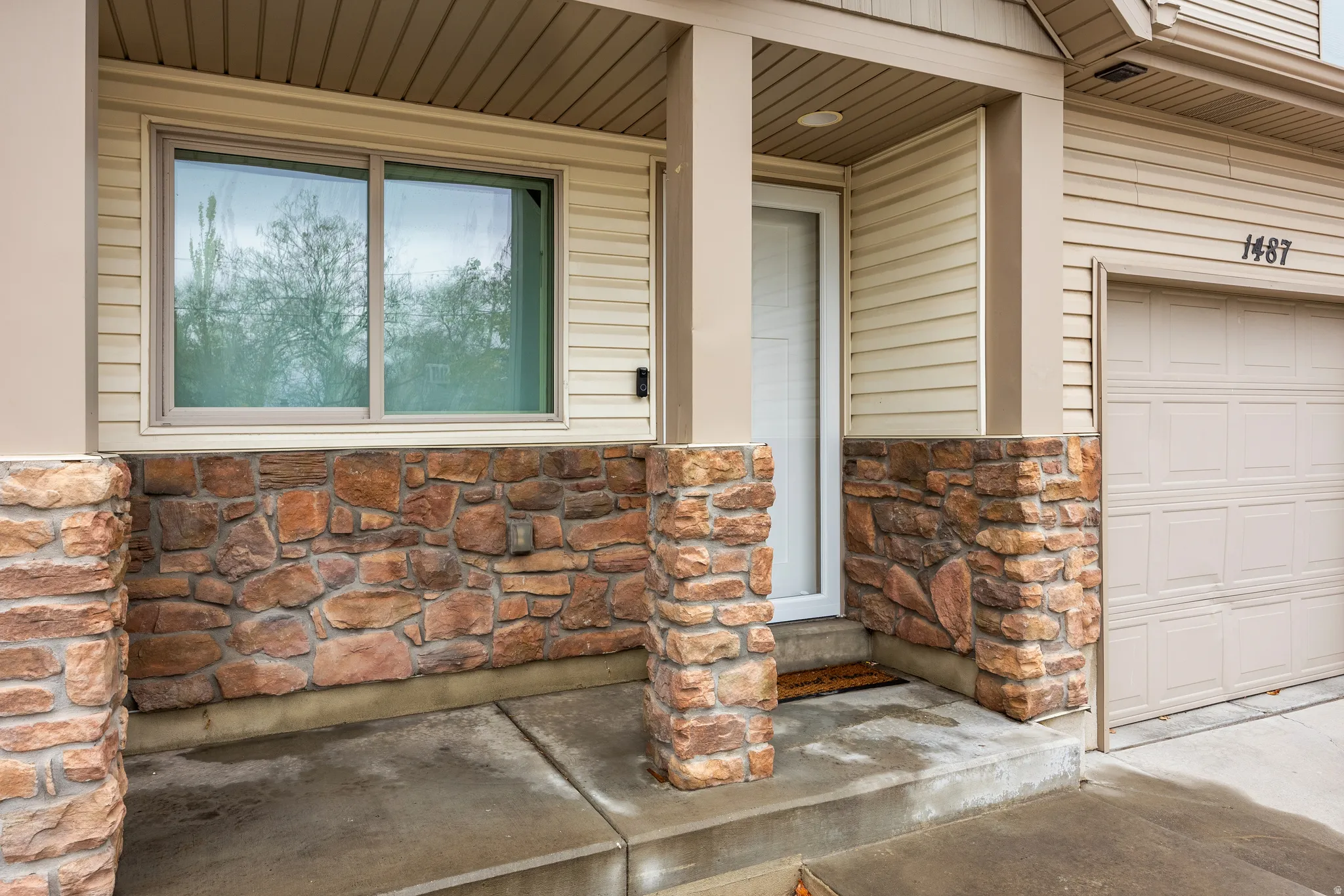 Property entrance featuring aluminum and stone siding and covered porch