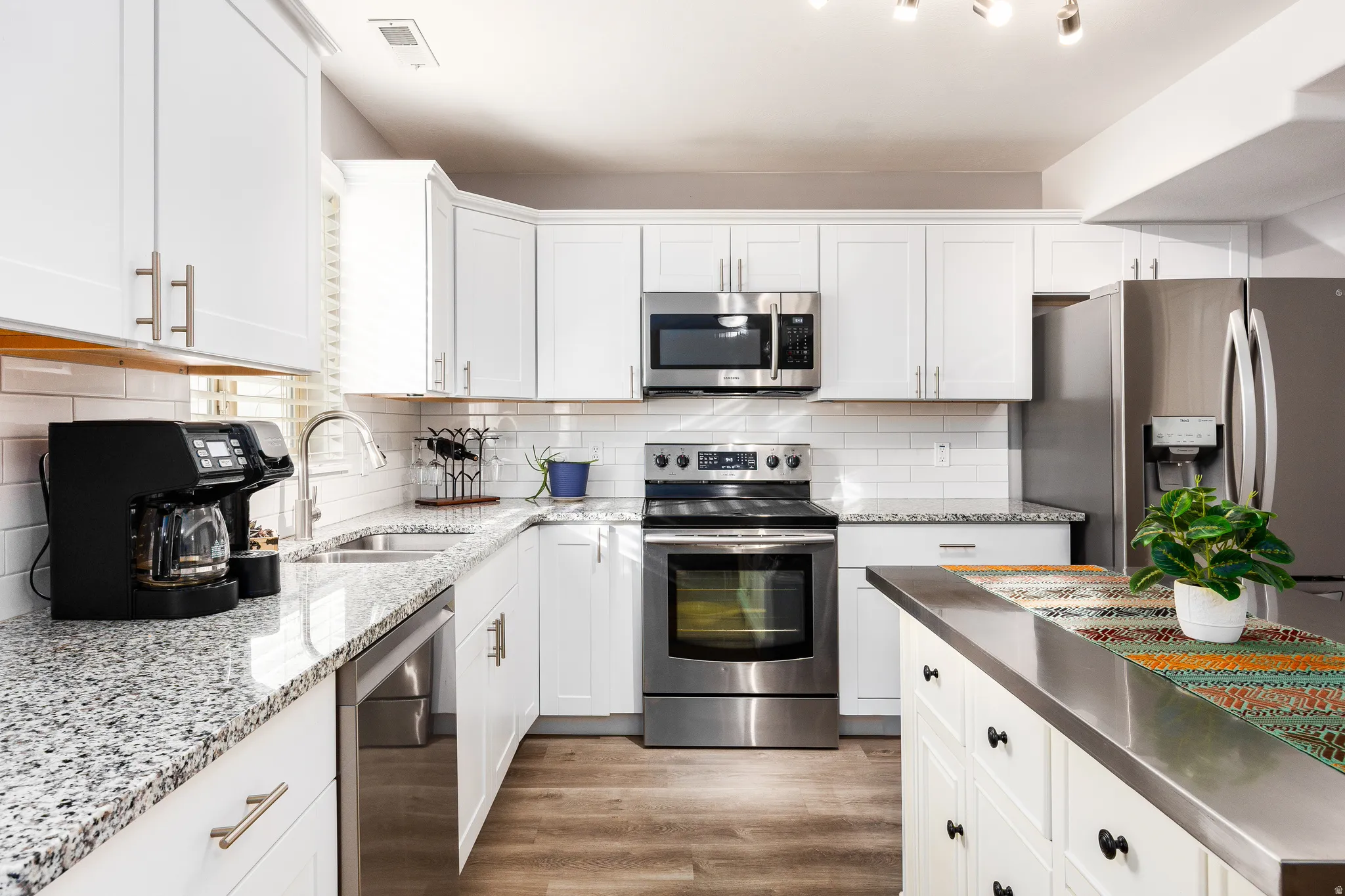 Kitchen featuring LVP flooring, decorative backsplash and granite countertops