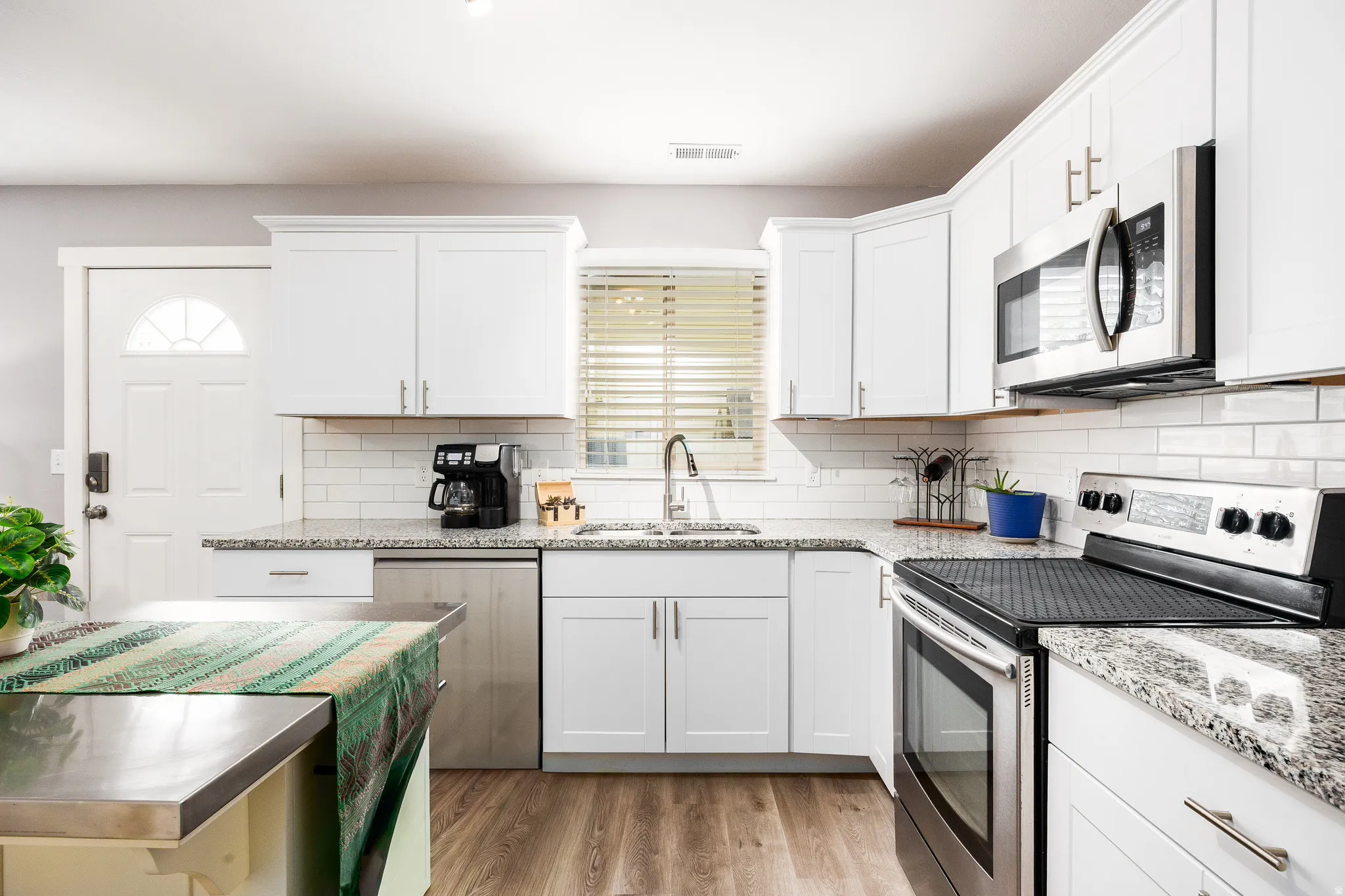 Kitchen featuring LVP flooring, decorative backsplash and granite countertops