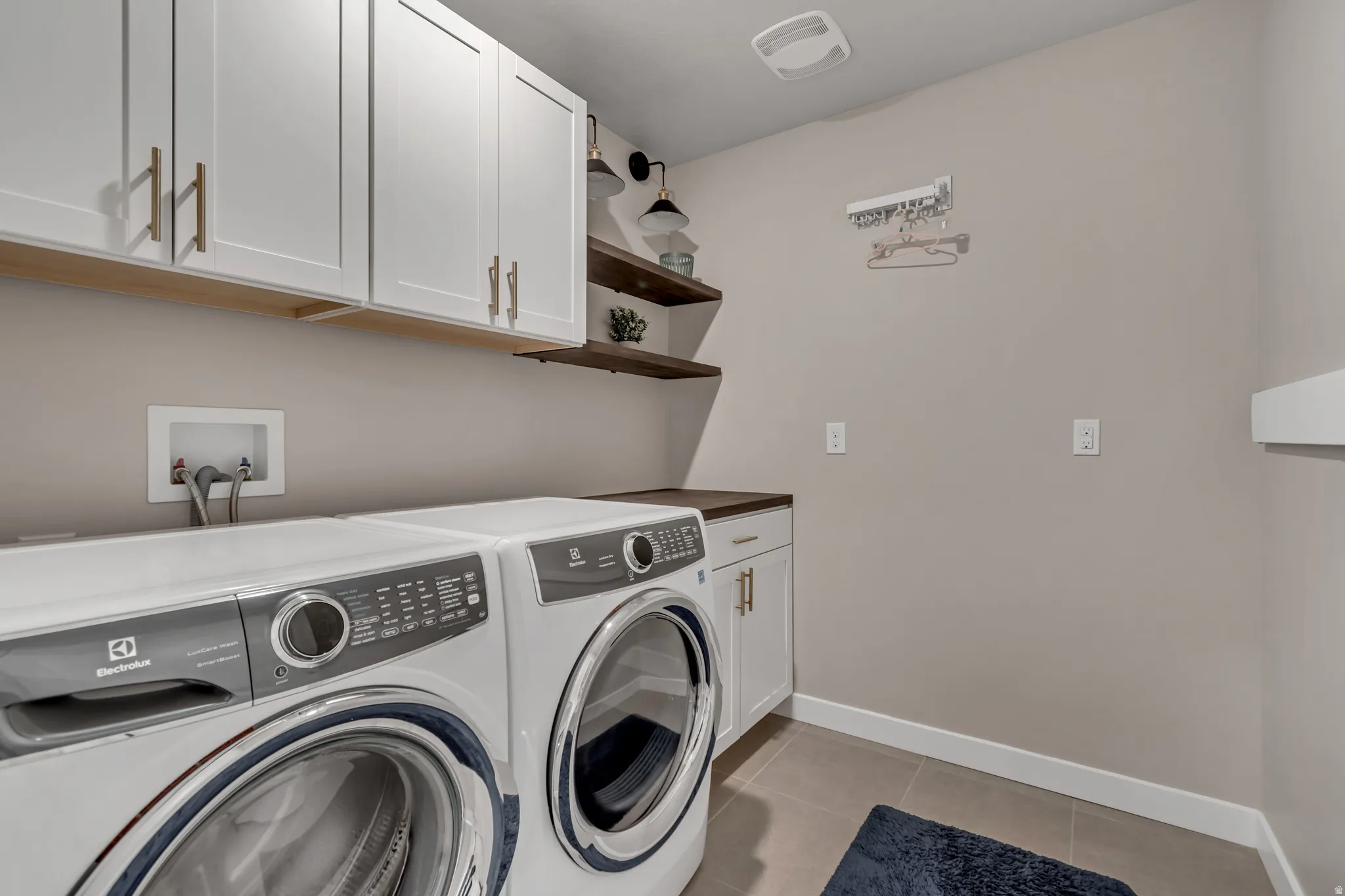 Laundry room featuring light tile patterned floors, cabinet space, and washing machine and dryer
