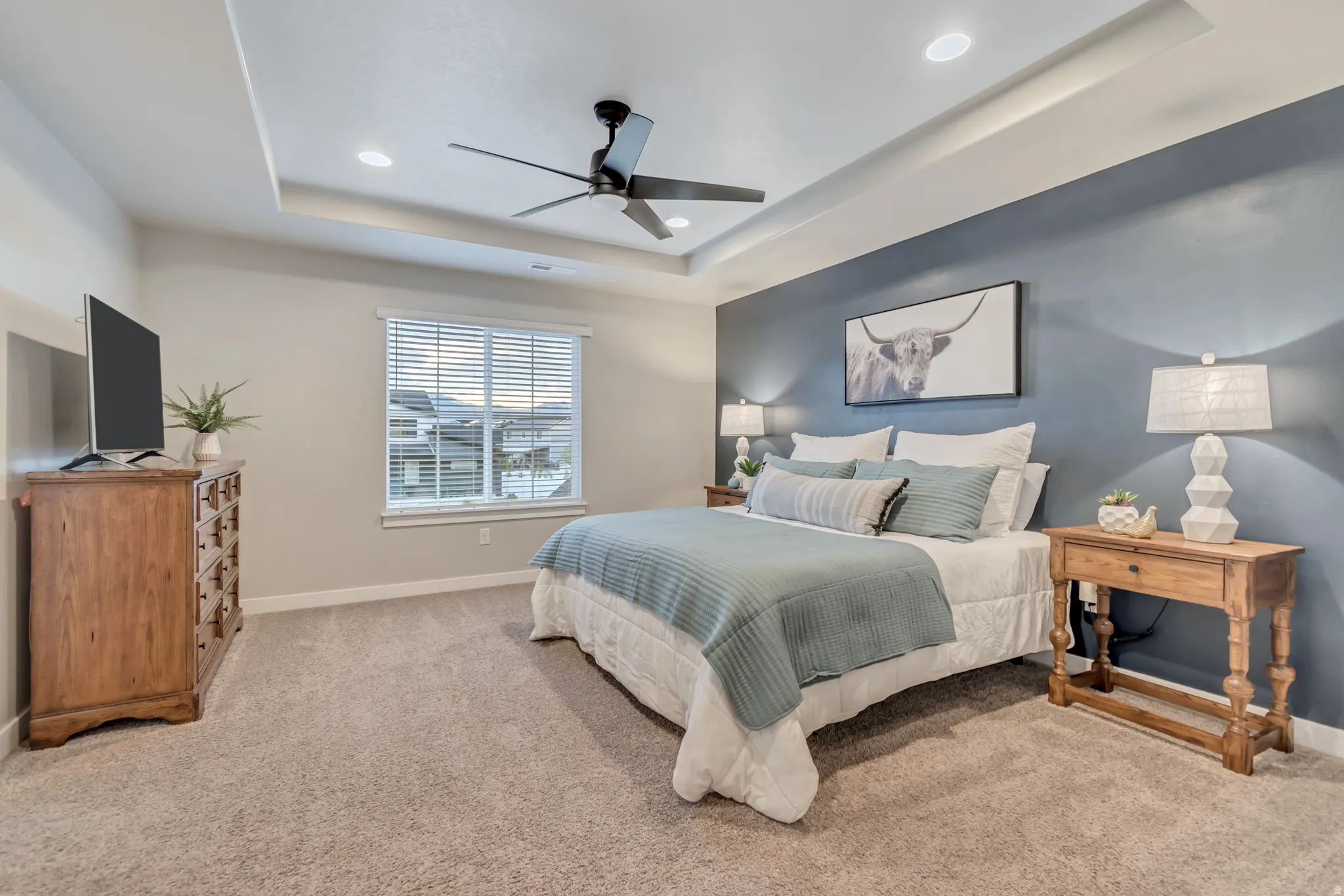Primary bedroom with light carpet, ceiling fan, recessed lighting, and tray ceiling