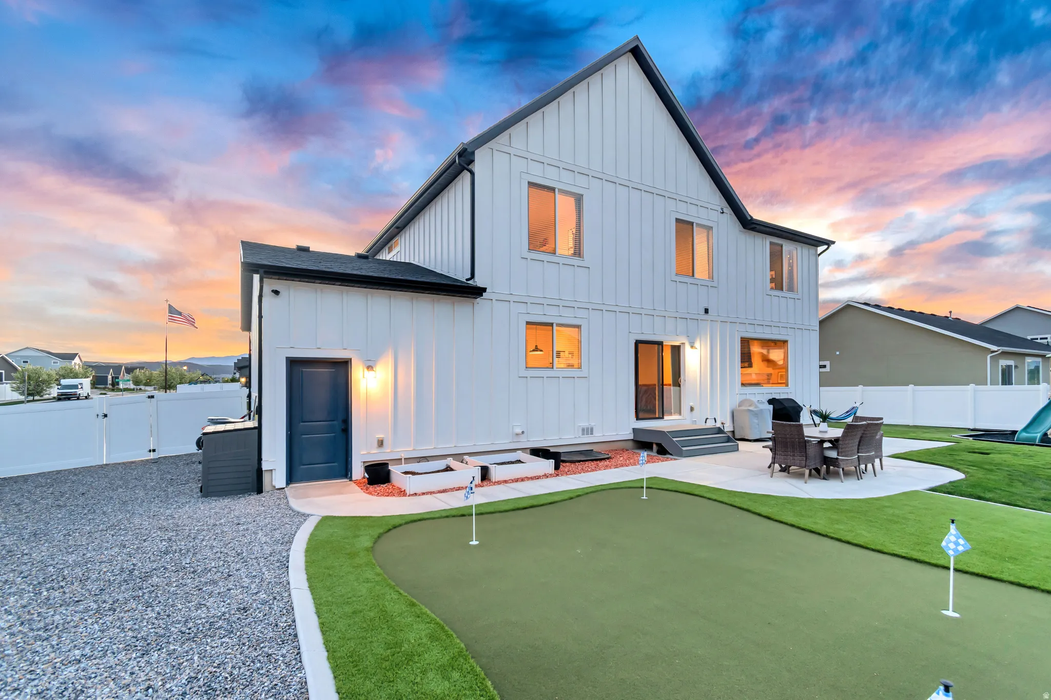 Back of house featuring board and batten siding, a fenced backyard, a patio, and an area to practice putting