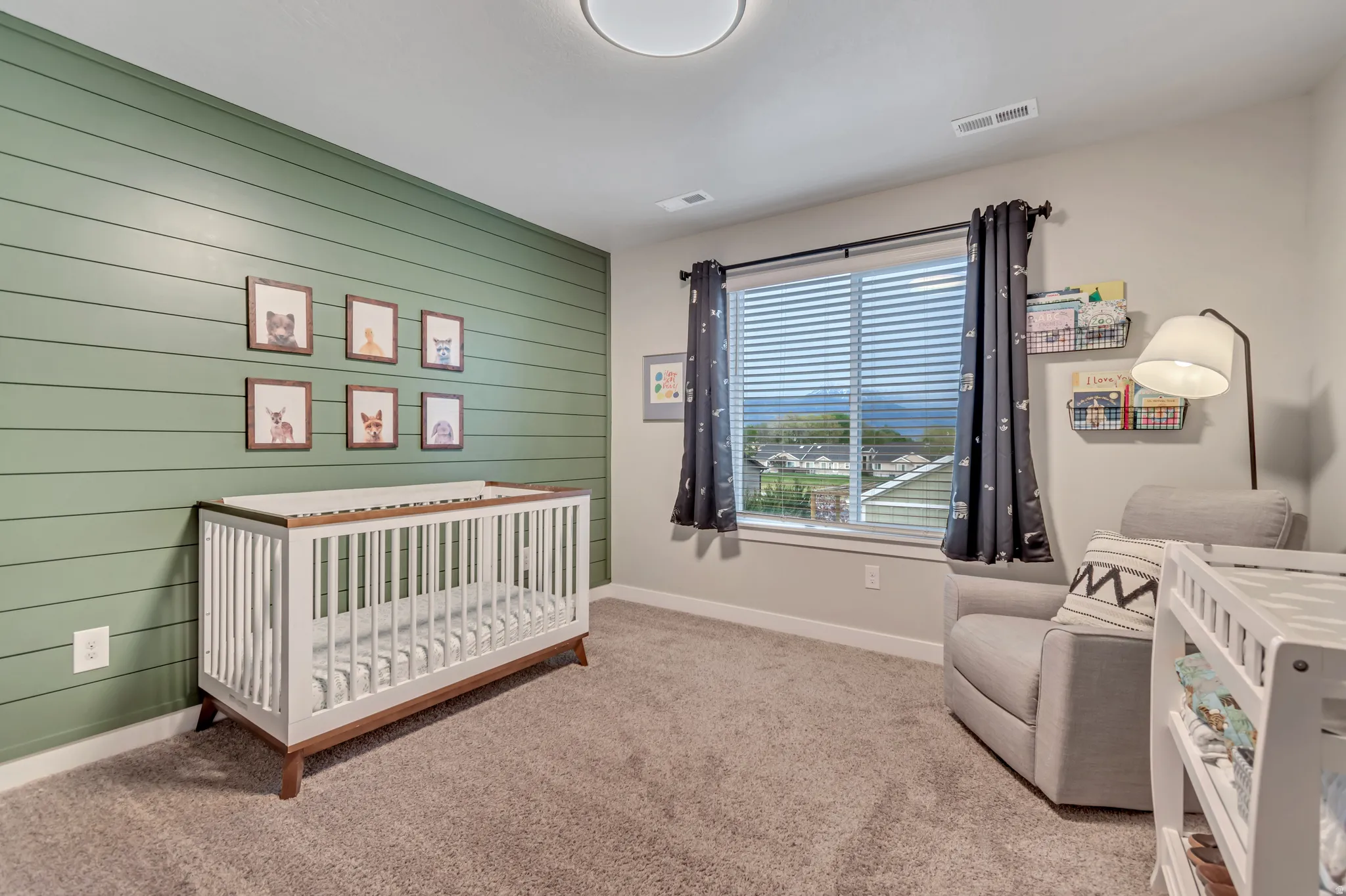 Bedroom featuring a nursery area, light colored carpet, and wooden walls