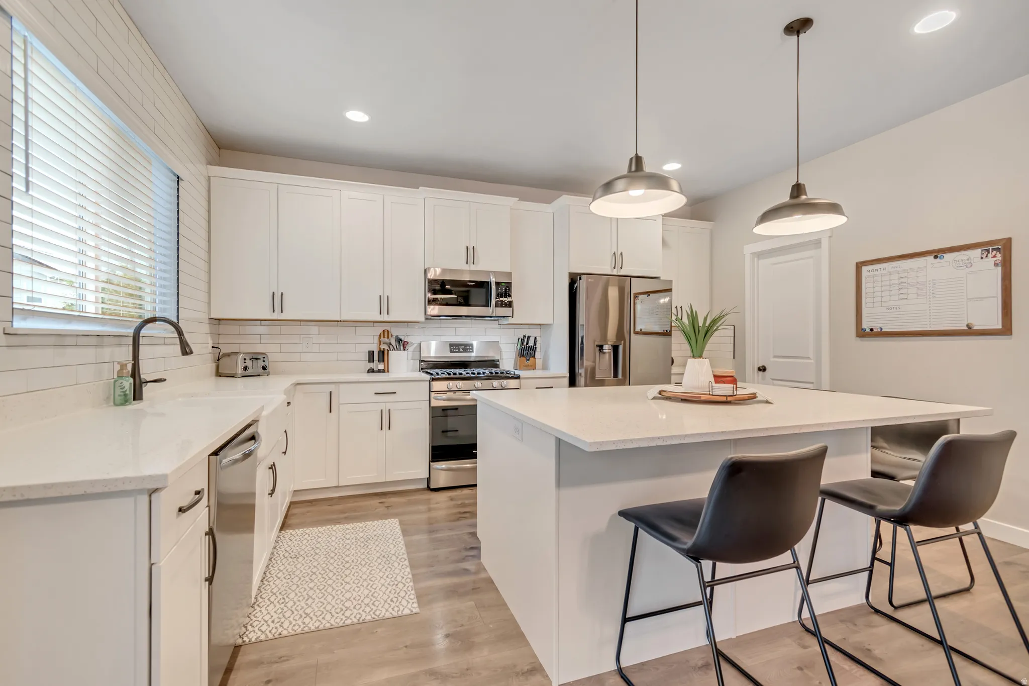 Kitchen featuring a center island, stainless steel appliances, a breakfast bar, and white cabinets and a large pantry