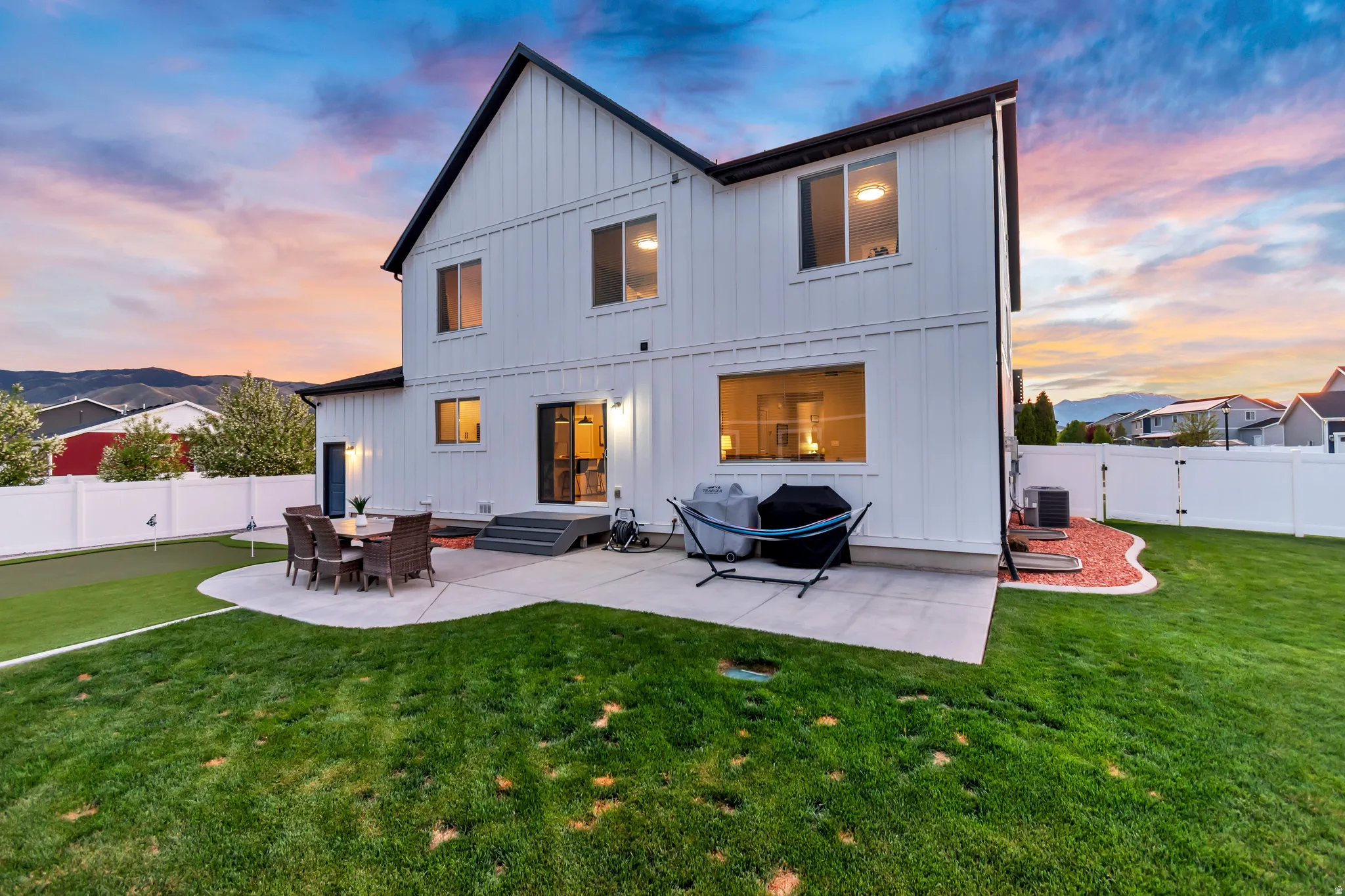 Rear view of property with board and batten siding, a patio, and fully fenced backyard
